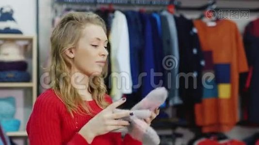 冬季购物。 一位年轻女子在一家服装店里试着戴暖手套视频