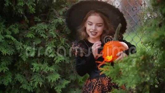 万圣节的小女巫在秋天的树叶背景下，女孩拿着南瓜点燃蜡烛亲吻视频