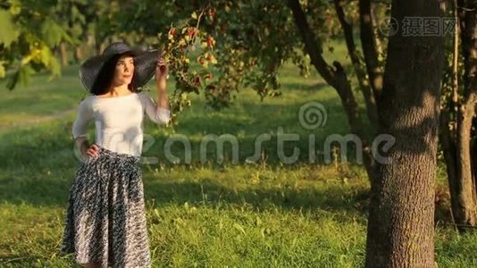 美丽迷人的女孩在温暖的夏日阳光下放松，一个漂亮的绿色水果花园视频