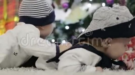 两个穿着水手装的婴儿趴在肚子上，在圣诞树附近爬行。视频