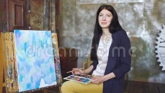年轻的女艺术家用水彩画画图画，微笑着看着镜头视频