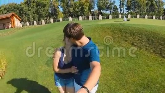 从摄像机拍摄的慢镜头拍摄的快乐年轻夫妇在公园接吻视频