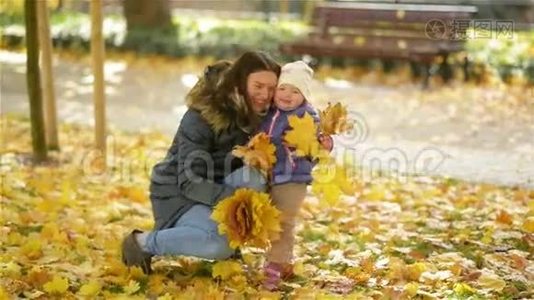 幸福的家庭，母子小女儿在大自然中嬉戏，抱着树叶，笑着拥抱秋天视频