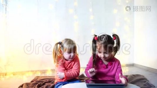 小女孩参与使用平板电脑，坐在明亮的房间里，墙上有花环。视频