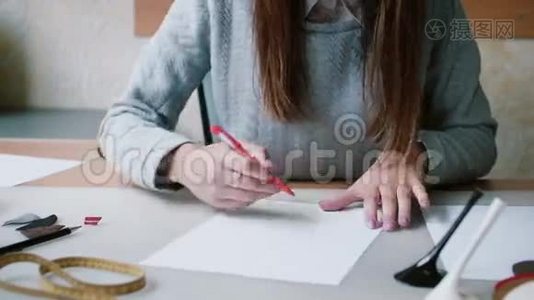 布鲁内特女士坐在桌子旁，拿着铅笔，在纸上画出布局。 在素描中擦除。 向左转。 4K视频