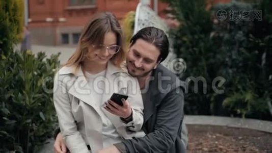 在大学附近的城市里，一对可爱的年轻漂亮夫妇在一起学习和玩后坐在地上视频