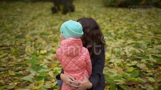 妈妈带着孩子在秋天公园。 快乐的年轻妈妈和小女孩在秋天的森林里休息。 慢动作视频