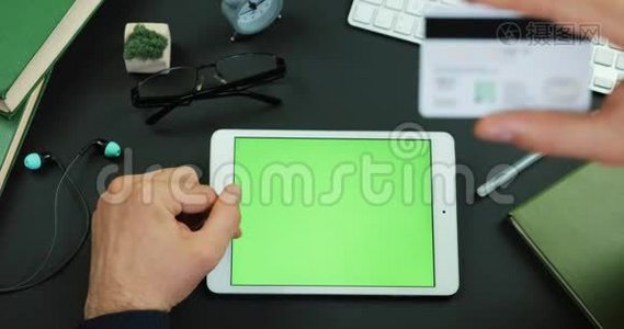 男人拿着绿色屏幕的平板电脑，在带有绿色屏幕的桌子上输入信用卡信息视频