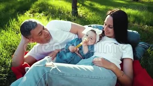 夏园绿草毯上抱着女婴的爱心家庭视频