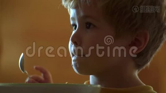 宝宝吃。 小男孩在厨房吃早餐。 快乐的小男孩勺子吃自己。 宝宝在厨房吃食物视频