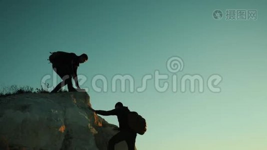 旅行者帮助登山者爬上一座山。 步行旅游徒步旅行冒险登山日落视频