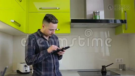 男人在平板电脑上看新闻，在厨房里喝咖啡视频