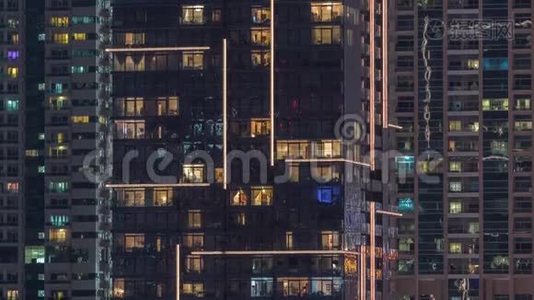 一排排发光的窗户，晚上公寓大楼里的人。视频