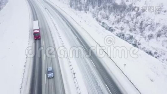 降雪时被冬季森林包围的道路上的交通鸟瞰图视频