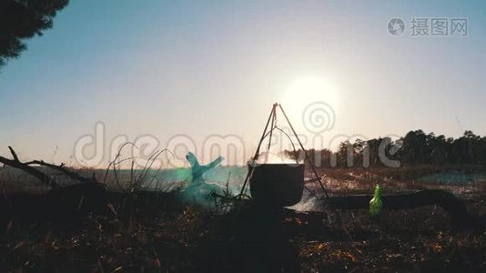 游客在篝火旁提供食物，在远足中烹饪，户外活动。 老水壶正烧在木桩上视频