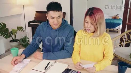 年轻时强调，亚洲夫妇管理财务，在现代家庭使用笔记本电脑和计算器审查他们的银行账户。视频