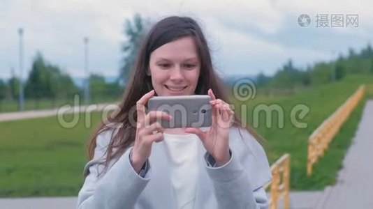 年轻女子在操场上用手机拍摄视频。视频
