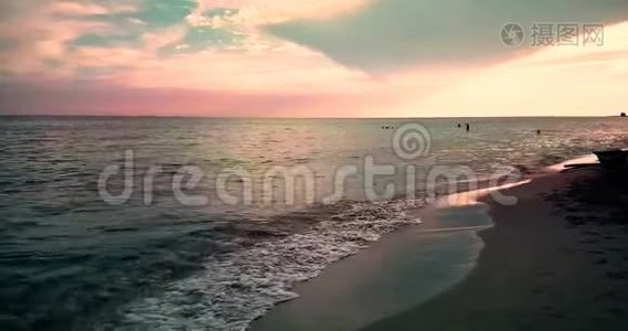 热带加勒比海海滩，日落时有金色沙滩，天空五彩缤纷，海洋运动缓慢，度假、放松和视频