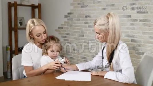 儿童健康检查。 年轻的母亲和她漂亮的小女儿去看儿科医生。 友好的儿童保健诊所视频