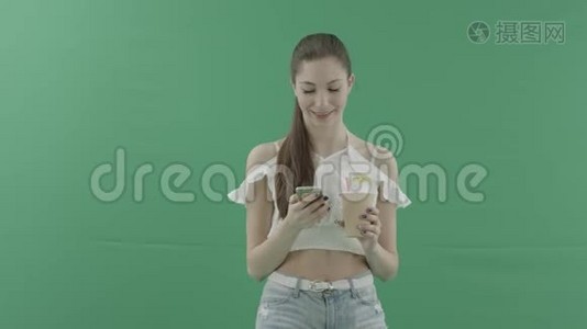 年轻貌美的女士，带着智能手机饮料和绿色背景的鸡尾酒视频