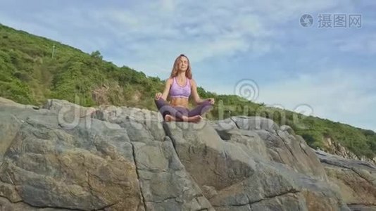 在岩石边缘坐着瑜伽姿势的女孩身上坐着一个机器人视频