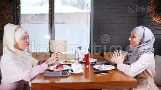 一个穆斯林女人坐在餐桌旁的咖啡馆里聊天视频