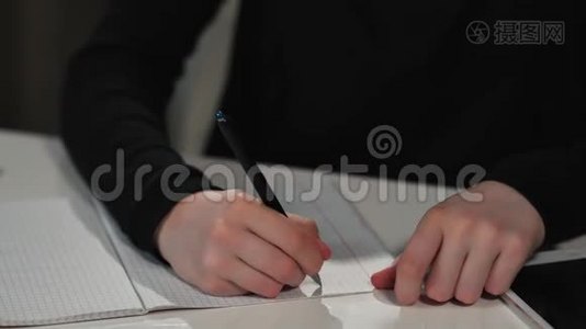 一个快乐的女学生用钢笔在练习本上写字。 她`在做作业。 特写视频