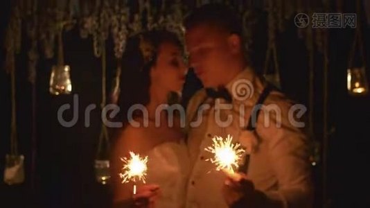 幸福的夫妻在户外燃烧孟加拉灯。 在这段时间里，新郎和新娘用爱看着对方视频