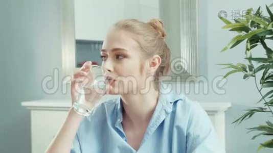 健康的年轻金发女人在家喝水的肖像。视频