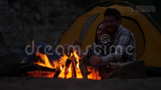 旅行和爱情的概念。 小可爱的一对在营地壁炉旁视频