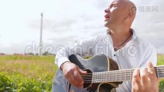 人在大自然中弹吉他，在田野里唱歌.. 吉他手触摸吉他弦。 中弹。视频