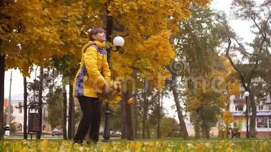 秋天公园里的女孩抛出了黄色的枫树叶子。 慢动作。视频