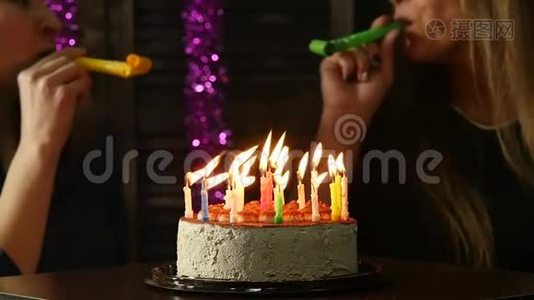 两个喜怒无常的女人吹灭了生日蛋糕上的蜡烛，蜡烛熄灭了。慢动作视频