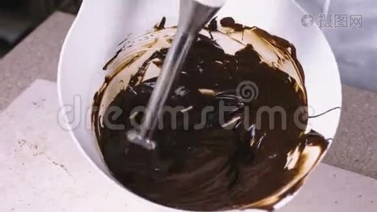 将液体黑巧克力与搅拌机混合在白色碗中。 特写镜头。视频