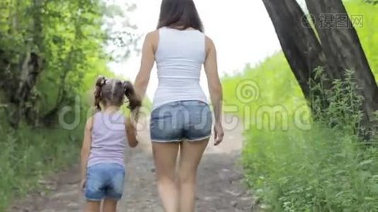 家庭价值观。 年轻的妈妈牵着小女孩的手在公园散步。 后退。视频