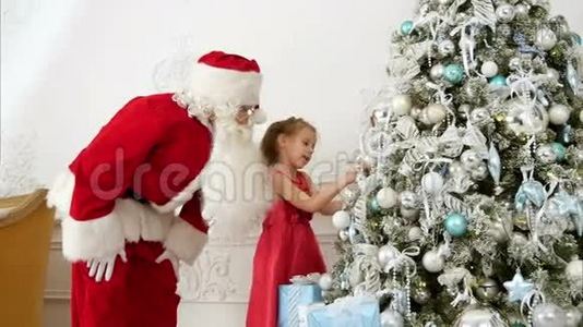 圣诞老人帮助漂亮的小女孩装饰圣诞树视频
