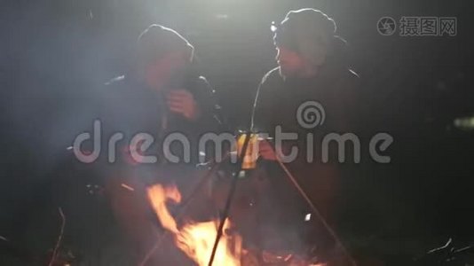 两个朋友晚上坐在柴火旁边，聊天喝茶..视频