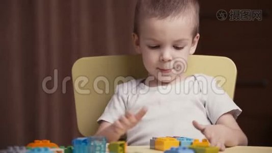 一个快乐的小男孩在家里玩一个五颜六色的建筑积木视频