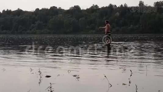 半裸的渔夫拿着鱼竿在平静的河里钓鱼视频