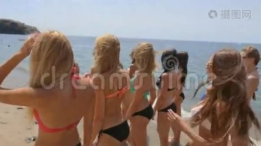 一群穿着比基尼的漂亮模特沿着海滩的海岸跑视频