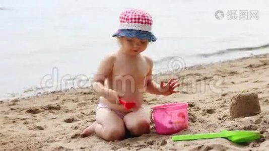 漂亮的小女孩在河边的海滩上玩铲子和沙子视频