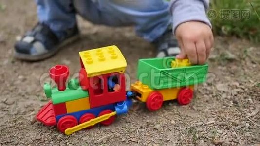 一个孩子在沙滩上玩玩具火车。 户外游戏视频