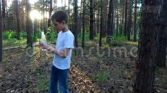 小男孩从瓶子里喝水。 日落时分在森林里的夏夜视频