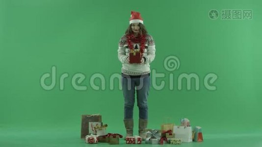 戴着圣诞帽的漂亮年轻女人看着她的圣诞礼物，背景色键视频
