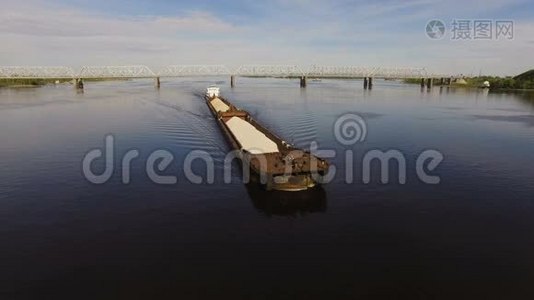 在桥的背景上，装满沙子和砾石的驳船漂浮在宽阔的河流上。 空中景观视频