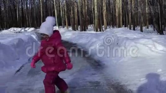 小女孩正在公园的冰道上跳舞。 女孩很高兴很快变得温暖。 春天晴朗的早晨视频