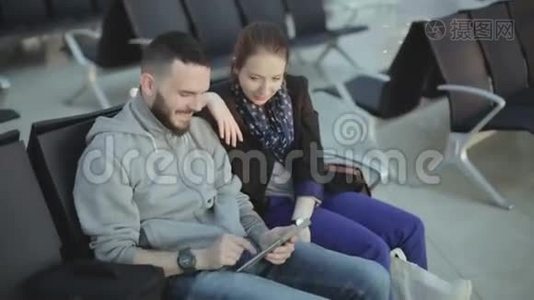 那家伙和穿着休闲服装的女孩正看着平板电脑屏幕笑着。视频