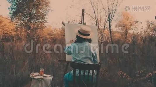 年轻的艺术家画一幅秋天的风景画。 艺术家绘画本质上的女孩视频