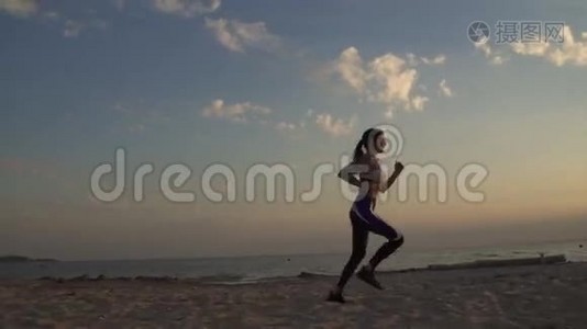 20岁的女孩在日落时在沙滩上奔跑。 在户外慢跑。视频