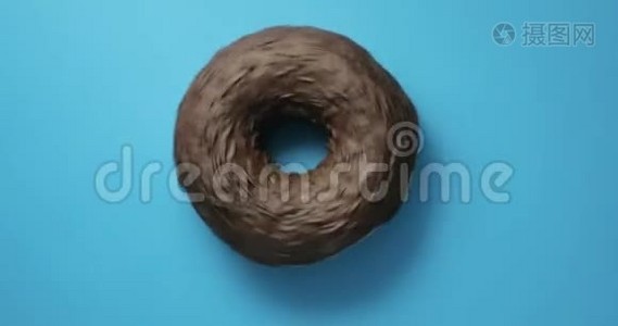 巧克力山核桃甜甜圈特写镜头旋转蓝色背景。 美味的甜面圈在盘子上旋转。 顶级视频